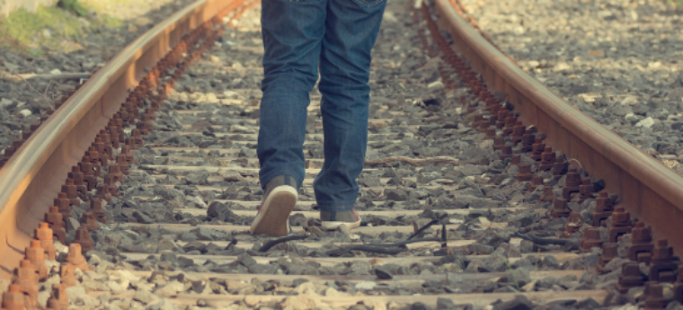Imagem mostra jovem caminhando pelo trilho de trem