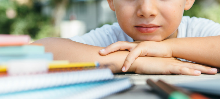 Imagem mostra estudante apoiado sobre uma mesa