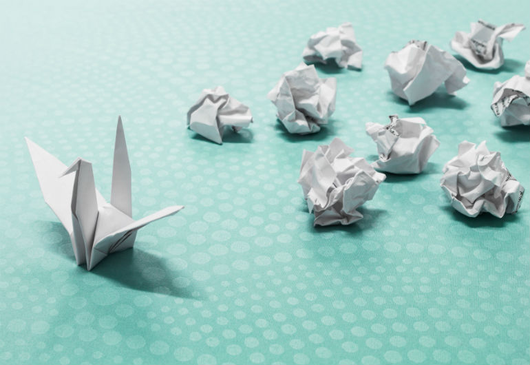 Pássaro de papel ao lado de bolinhas transmitindo a ideia de sucesso após várias tentativas
