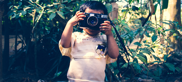 Criança pequena tira foto em meio a floresta