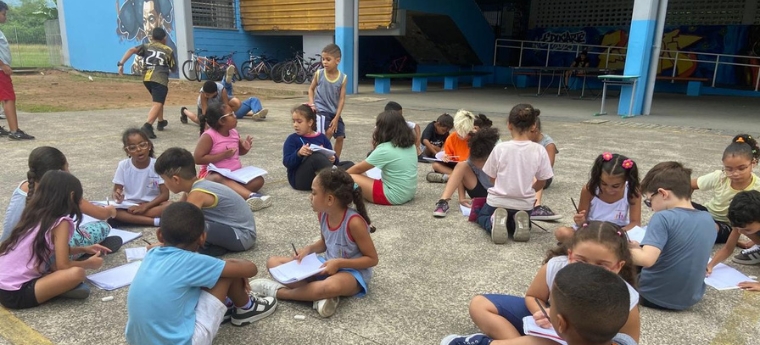 Crianças fazem atividades em grupo no pátio de uma escola.