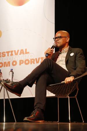 Homem de terno segurando um microfone durante sua fala no Festival Encontro com o Porvir