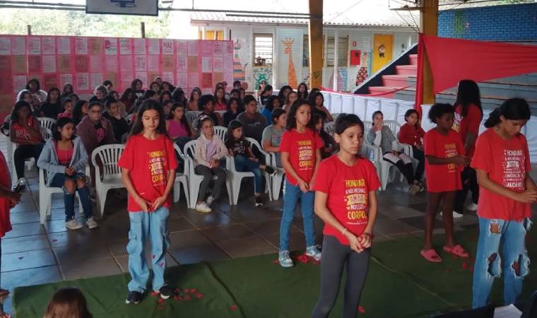 Meninas participam de ato simbólico com pétalas, em atividade sobre autoestima e respeito ao corpo.