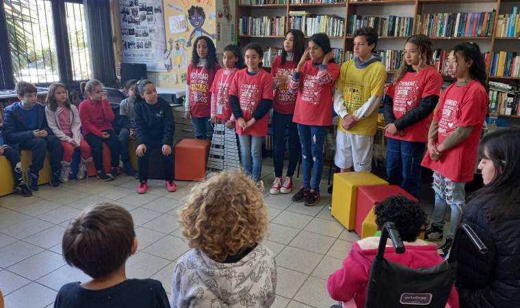Jovens se apresentam para crianças em uma biblioteca, com foco em temas de valorização do corpo e educação.