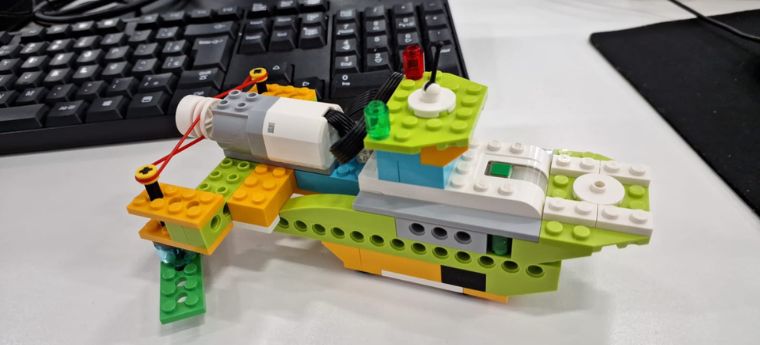 Maquete de embarcação feita com blocos de montar sobre mesa com teclado.