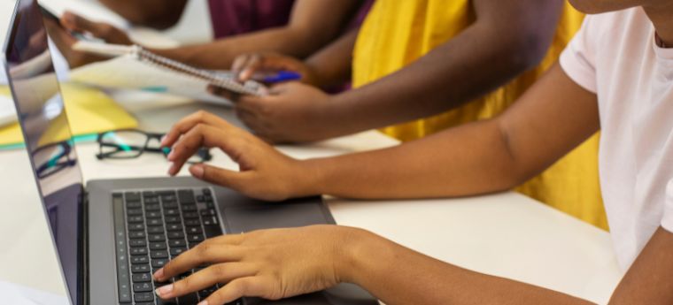 Pessoas escrevendo e digitando juntas em ambiente de estudo.