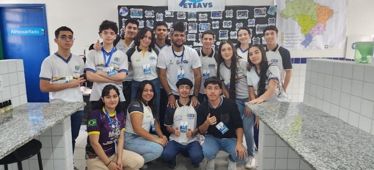 Grupo de estudantes da ETE posando para foto em sala de aula com painel ao fundo.