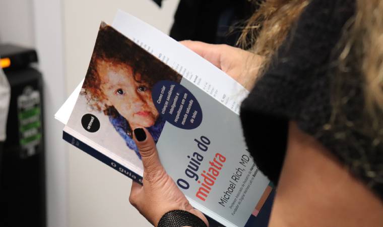 Pessoa segurando o livro “O guia do midiatria”, com capa mostrando rosto de uma criança.