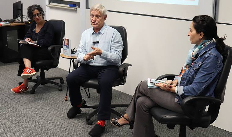 Três pessoas participam de roda de conversa com o livro “O guia do midiatria” em destaque.