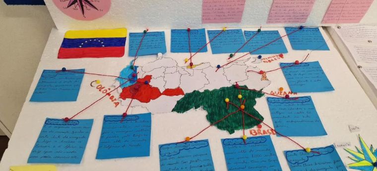 Mapa colorido da Venezuela com linhas conectando regiões a notas adesivas coloridas. As notas contêm informações manuscritas sobre as regiões. Uma bússola e a bandeira da Venezuela estão visíveis ao lado.