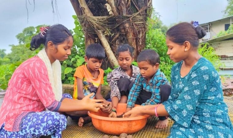 Crianças modelando barro em grupo ao ar livre, em ambiente rural.