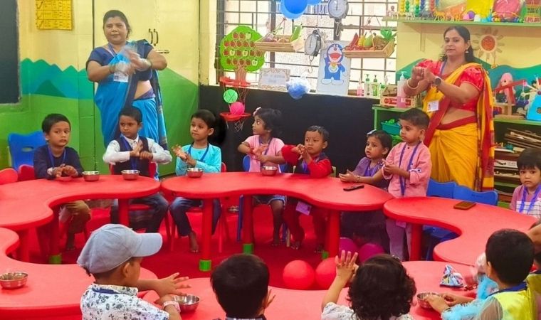 Crianças pequenas participam de atividade guiada por duas professoras em sala colorida.