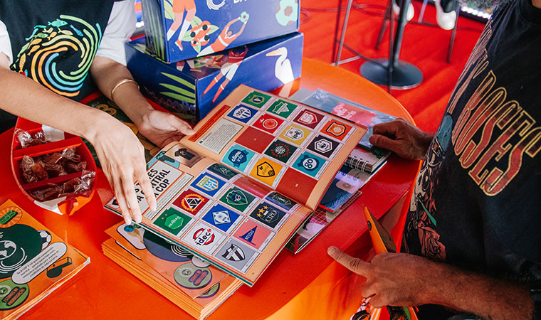 Duas pessoas folheiam página com logos de organizações no álbum COP 30