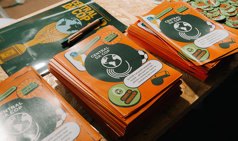 Pilhas de revistas da Central da COP 30 sobre mesa de madeira