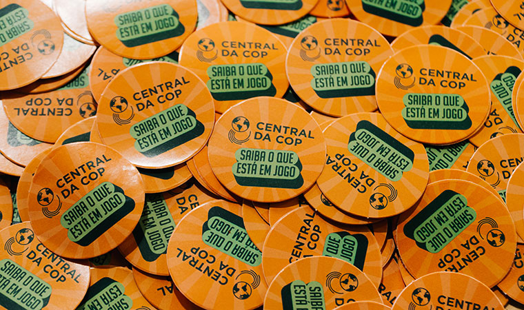 Adesivos redondos laranja com a frase “Saiba o que está em jogo”