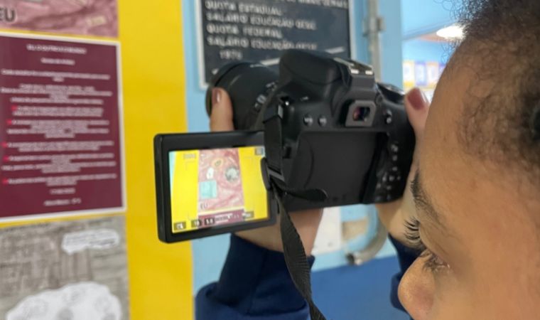 Jovem fotografa cartaz colorido em ambiente escolar