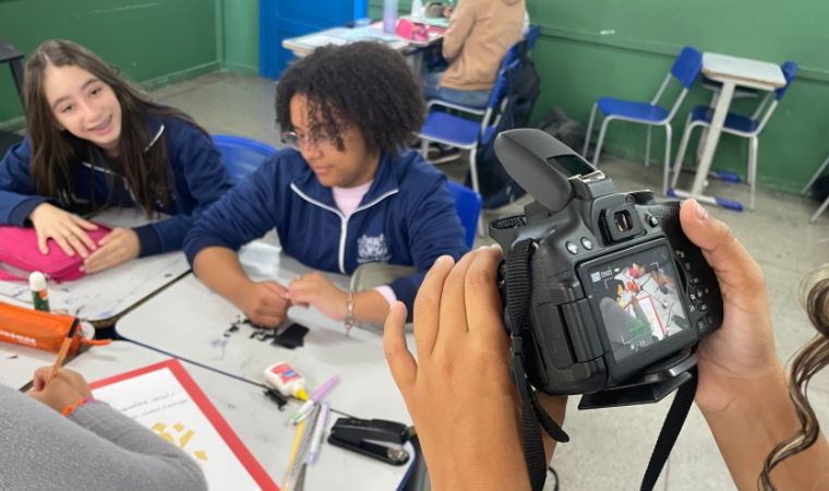 Duas alunas são filmadas enquanto trabalham em grupo na escola