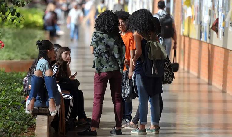 Grupo de estudantes conversa em corredor escolar