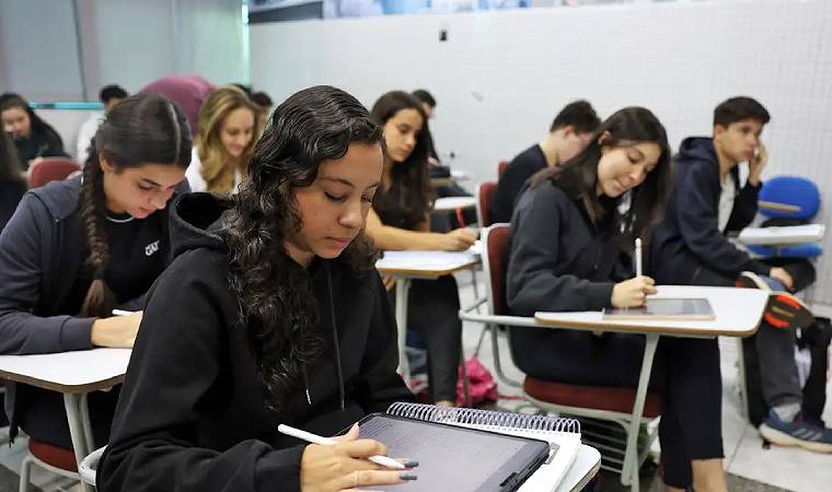 Alunos escrevendo em sala de aula com tablets