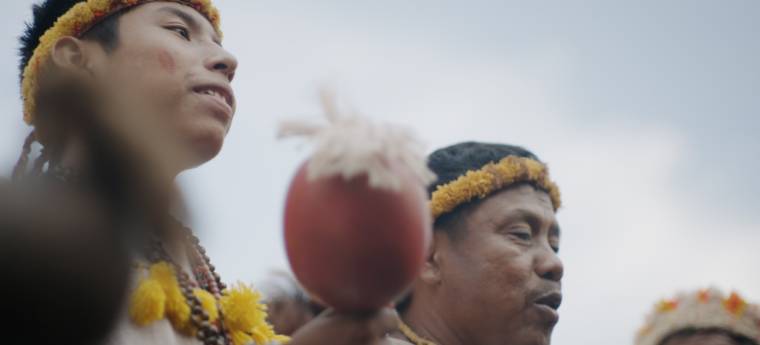 Indígenas com cocares e maracá participam de canto tradicional