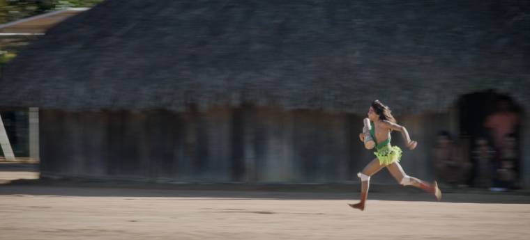 Menina corre descalça segurando objeto em aldeia
