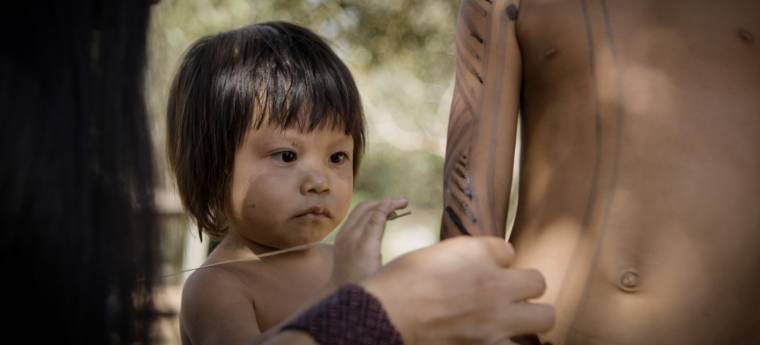 Menina pequena indígena toca palha durante atividade