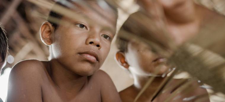 Menino observa atentamente palha usada em artesanato