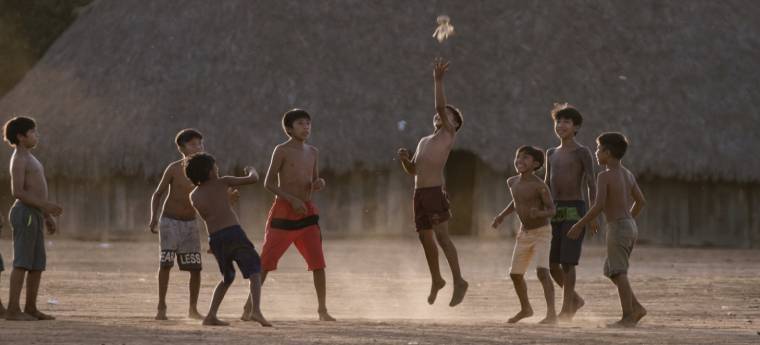 Grupo de meninos indígenas jogando em campo de terra batida