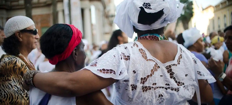 Mulheres vestidas com roupas tradicionais brancas participam de manifestação cultural