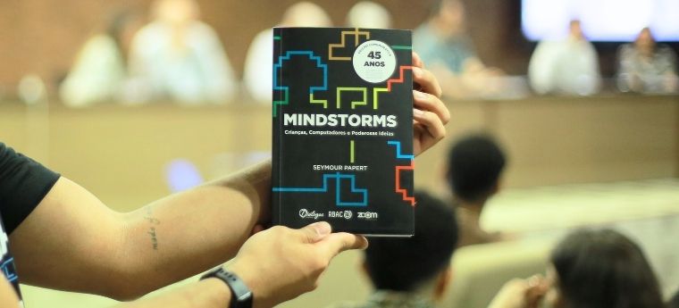 Pessoa segura exemplar do livro “Mindstorms” em frente a auditório
