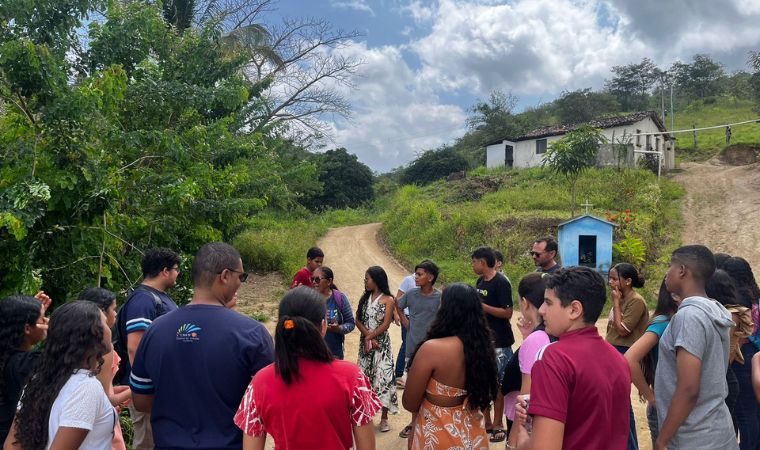 Grupo em círculo conversa em estrada de terra cercada por vegetação