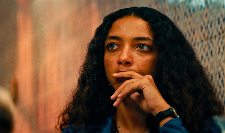 Mulher jovem com expressão séria, com a mão sobre a boca