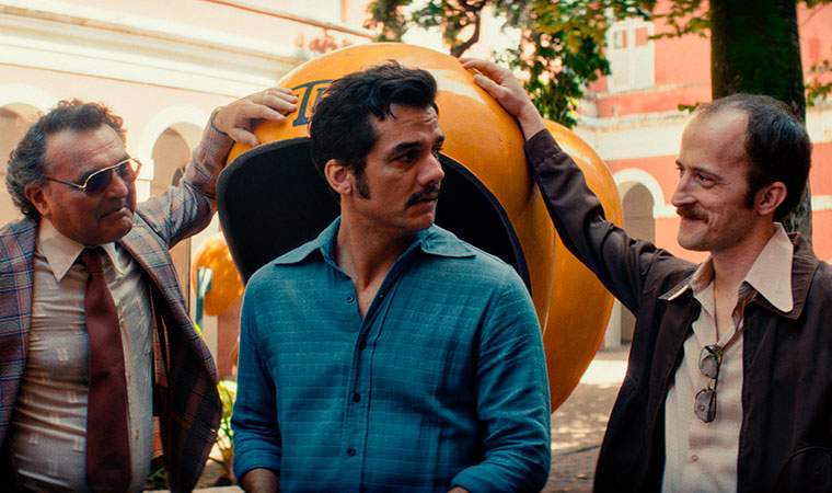 Três homens falam próximos a orelhão público