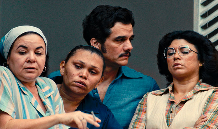 Quatro adultos olham para fora do quadro com expressões sérias