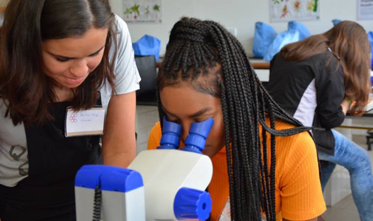 Estudantes observam amostras em microscópio durante atividade científica