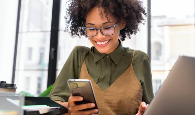 Mulher sorrindo ao usar smartphone no escritório