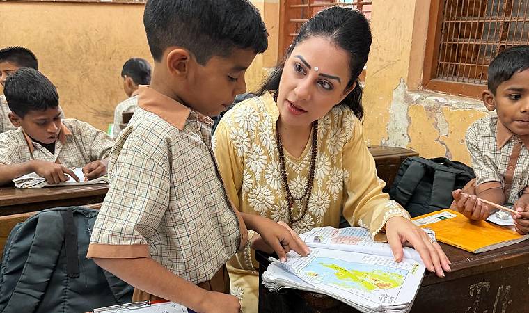 Rouble Nagi aponta para livro de geografia enquanto conversa com aluno