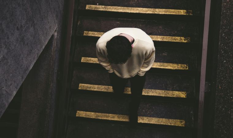 Pessoa desce escada com marca&ccedil;&otilde;es de seguran&ccedil;a em ambiente urbano